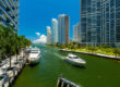 Image of yachts in the Miami river docked alongside the shore and crusing